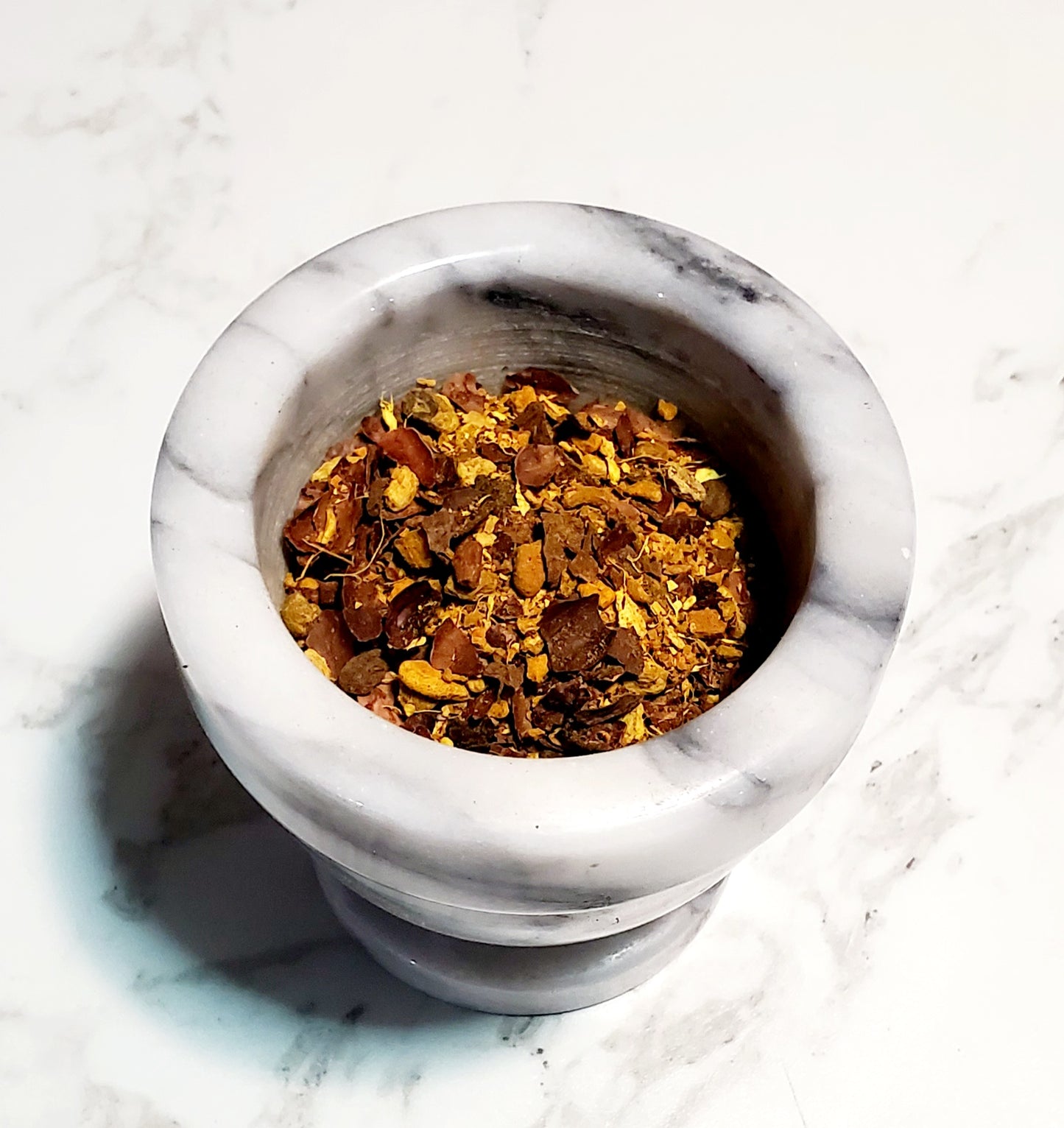 Mortar with dried herbs on a marble surface