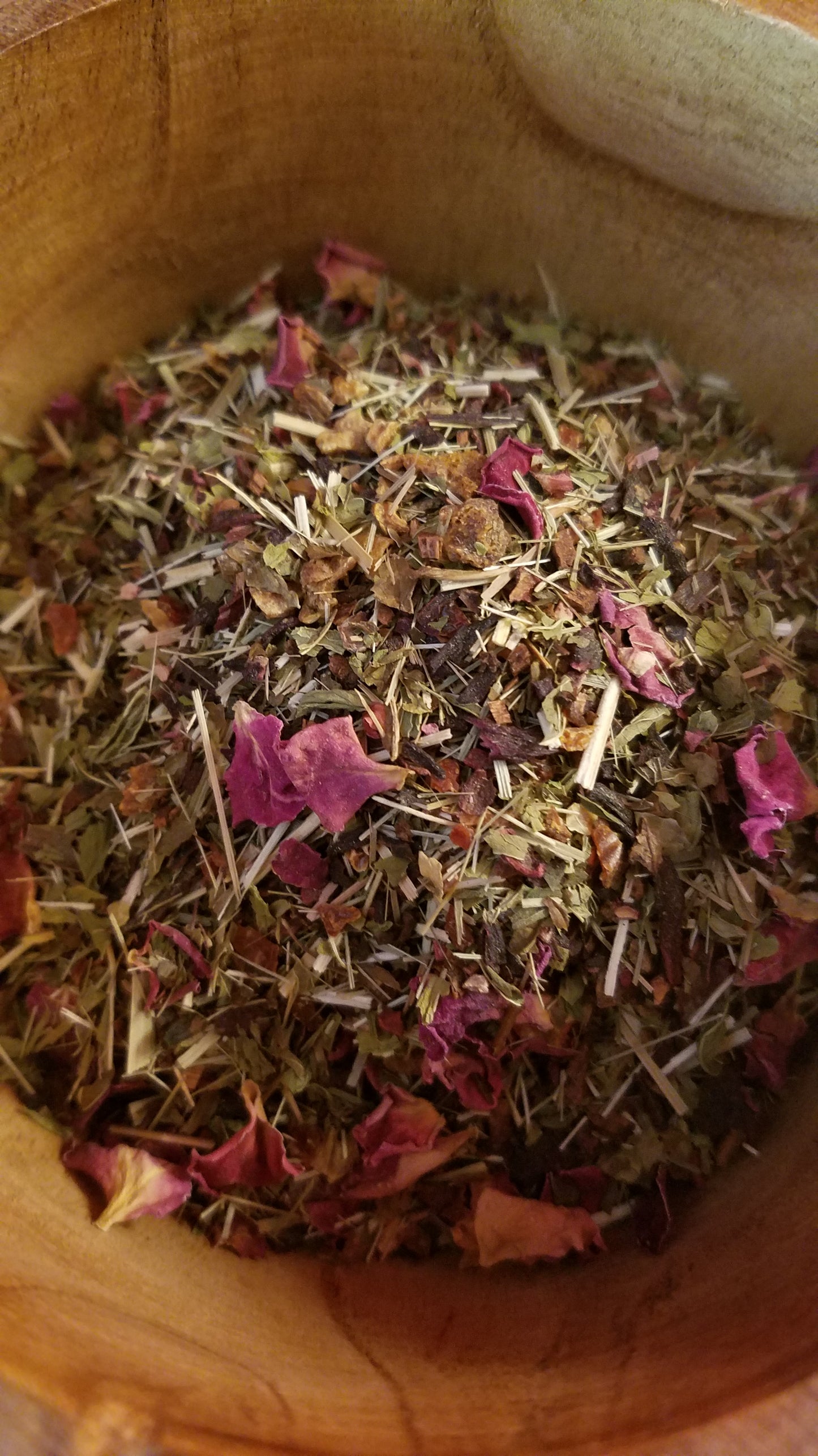 Wooden mortar filled with dried flowers and herbs.